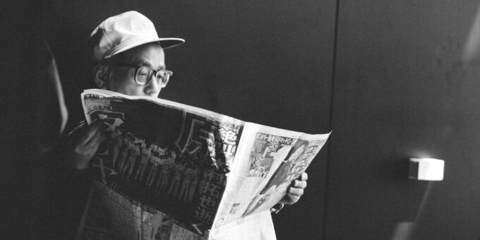 man in black shirt reading newspaper