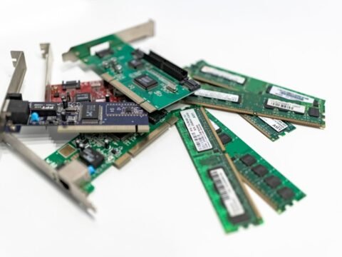 A detailed close-up of computer RAM sticks and PCI cards arranged on a white surface for tech illustration.