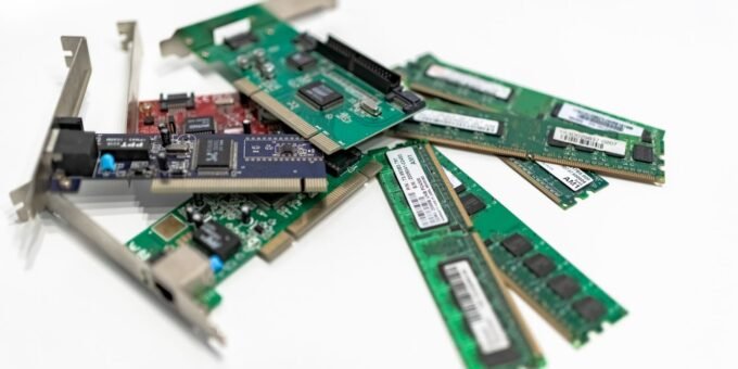 A detailed close-up of computer RAM sticks and PCI cards arranged on a white surface for tech illustration.
